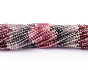 May include: A strand of pink, red, and gray gemstone beads. The beads are round and have a faceted finish. The beads are strung on a clear thread.