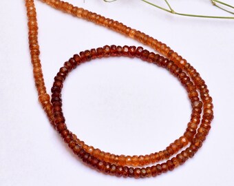 May include: A strand of brown and orange gemstone beads. The beads are faceted and have a slightly irregular shape. The strand is approximately 18 inches long.