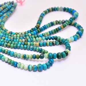 Op de afbeelding: Een streng turquoise edelsteen kralen in tinten blauw en groen. De kralen zijn rond en hebben een gladde, gepolijste afwerking.