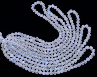 May include: A strand of white moonstone beads with iridescent blue and green flashes. The beads are round and smooth, and they are strung on a clear thread.