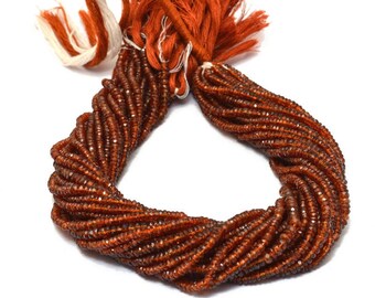 May include: A strand of brown gemstone beads, likely garnet, with a tassel at the end. The beads are faceted and have a shiny finish. The strand is coiled and ready for use in jewellery making.