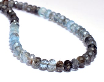 May include: A strand of faceted gemstone beads in shades of blue and gray. The beads are graduated in size, with the larger, darker beads at one end and the smaller, lighter beads at the other.