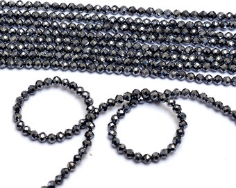 May include: A strand of black faceted beads, with some of the beads strung into a circle.