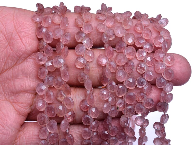 May include: Close-up of strands of pink gemstone beads. The beads are faceted, with a mix of round and teardrop shapes. The gemstones have a delicate, translucent quality and are strung together. The beads have a subtle sparkle and are a soft pink colour.