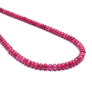 Könnte beinhalten: Eine Kette aus rosafarbenen Edelsteinperlen, auf einer dünnen Schnur aufgefädelt. Die Perlen sind rund und haben eine leicht unregelmäßige Form. Die Halskette ist etwa 45 cm lang.