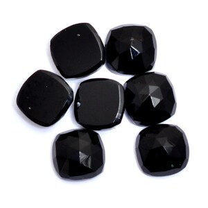 May include: Seven black gemstone cabochons in a variety of shapes and sizes. The stones are smooth and polished, with a glossy finish.