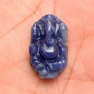 May include: A carved, deep blue gemstone figurine of the Hindu deity Ganesha. The figurine is detailed with visible features like the elephant head, large ears, and seated posture. The stone has a polished finish.