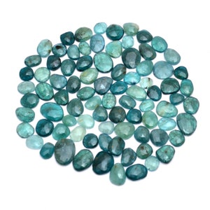 May include: A collection of teal blue gemstone cabochons, with a variety of shapes and sizes. The stones are faceted and have a smooth, polished finish.