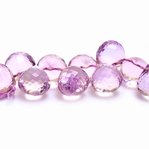 May include: A strand of faceted amethyst beads in shades of light and dark purple. The beads are strung on a thin, pink thread.
