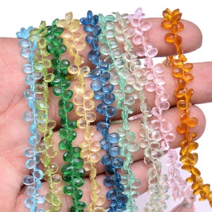 May include: Assortment of faceted gemstone beads in various colours, including blue, green, yellow, pink, and orange. The beads are shaped like small leaves and are strung together on a string.