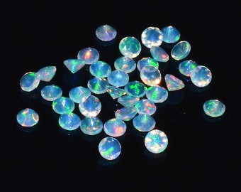 Pode incluir: Uma coleção de gemas de opala iridescente em vários tons de azul e verde, espalhadas sobre um fundo preto.