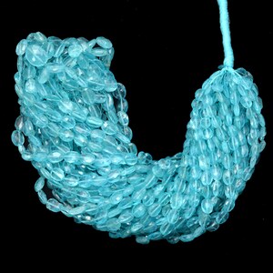May include: A strand of light blue aquamarine gemstone beads. The beads are oval shaped and have a smooth, polished finish.