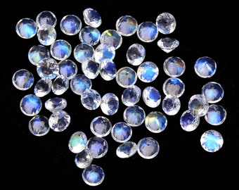 May include: A collection of iridescent moonstone gemstones, each with a unique blue and white shimmer. The stones are round and faceted, and they are scattered on a black background.