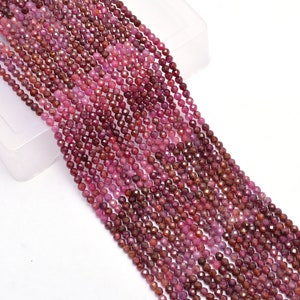 May include: A strand of ruby red faceted gemstone beads. The beads are small and round, and they are strung on a clear thread. The beads are arranged in a straight line, and they are all the same size and shape.