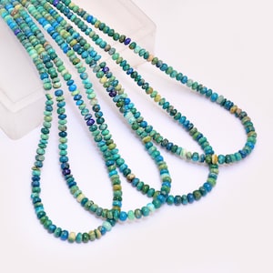 Op de afbeelding: Een streng turquoise edelsteen kralen in verschillende tinten blauw en groen. De kralen zijn rond en hebben een gladde, gepolijste afwerking. De streng is ongeveer 45 cm lang.