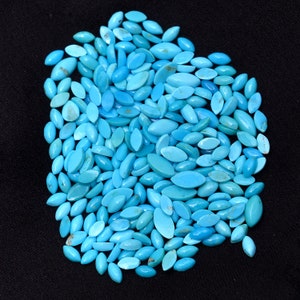Pode incluir: Um grande monte de caboch&otilde;es turquesa em forma de l&aacute;grima. As pedras s&atilde;o de uma cor azul-verde vibrante e est&atilde;o dispostas em um padr&atilde;o aleat&oacute;rio.