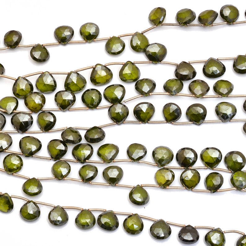 May include: A strand of dark green gemstone beads, each bead is faceted and shaped like a teardrop. The beads are strung on a silver wire.