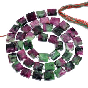 以下が含まれることがあります： 正方形の緑とピンクの宝石ビーズのストランド。ビーズは白い糸に糸に通され、各宝石ビーズの間に小さな白いビーズが置かれています。