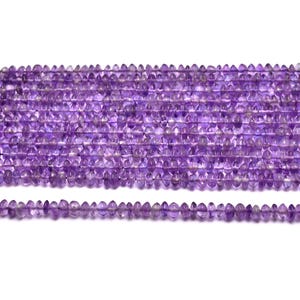 Puede incluir: Una hebra de cuentas de amatista, cada cuenta está facetada y tiene una forma puntiaguda. Las cuentas son de color morado claro y están enhebradas en un hilo transparente.