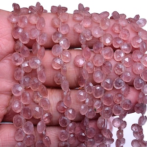 May include: Close-up of strands of pink gemstone beads. The beads are faceted, with a mix of round and teardrop shapes. The gemstones have a delicate, translucent appearance and are strung together. The beads have a subtle sparkle and are a soft pink colour.