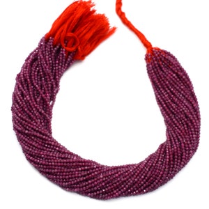 Puede incluir: Una hebra de cuentas de rubí rojo intenso, de aproximadamente 2 mm de tamaño, con un borla roja en el extremo. Las cuentas son facetadas y tienen un acabado brillante.