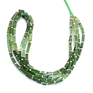 Peut inclure: Collier de perles de tourmaline verte avec des espaceurs blancs, enfilées sur un cordon vert. Les perles cylindriques varient en nuances de vert, créant une esthétique naturelle et terreuse. Idéal pour la création de bijoux.