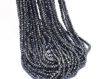 May include: A strand of black faceted gemstone beads. The beads are small and round, and they have a shiny, metallic finish.