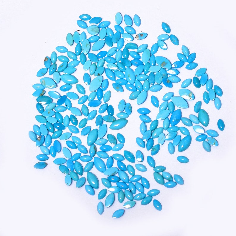Pode incluir: Uma grande cole&ccedil;&atilde;o de caboch&otilde;es de turquesa em uma variedade de tamanhos e formas. As pedras s&atilde;o de cor azul claro e t&ecirc;m um acabamento liso e polido.