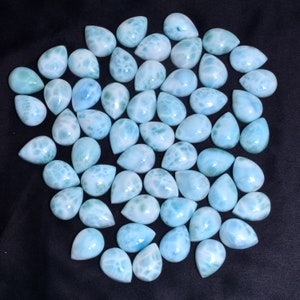 May include: A collection of 40 teardrop-shaped, light blue, iridescent gemstone cabochons. The stones have a cloudy, marbled appearance.