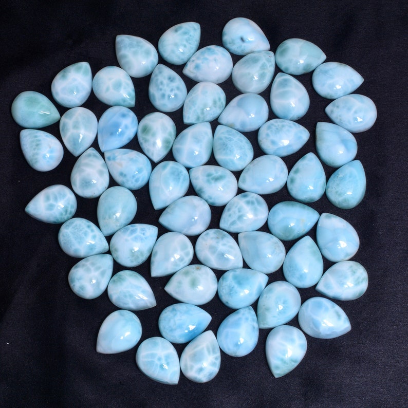 May include: A collection of 40 teardrop-shaped, light blue, iridescent gemstone cabochons. The stones have a cloudy, marbled appearance.