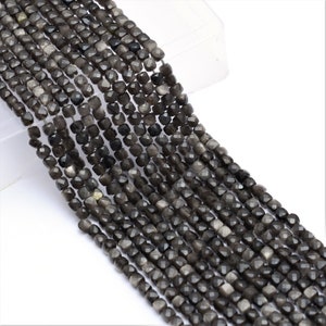 Peut inclure: Un brin de perles de pierres précieuses facettées grises. Les perles sont de forme carrée et ont une finition chatoyante.