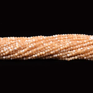 May include: A strand of light peach-coloured shell beads. The beads are faceted and have a slightly iridescent sheen.