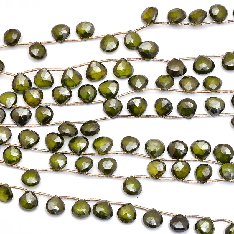 May include: A strand of dark green gemstone beads, each bead is faceted and shaped like a teardrop. The beads are strung on a silver wire.