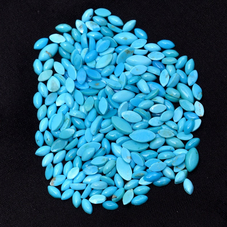 Pode incluir: Um grande monte de caboch&otilde;es turquesa em forma de l&aacute;grima. As pedras s&atilde;o de uma cor azul-verde vibrante e est&atilde;o dispostas em um padr&atilde;o aleat&oacute;rio.