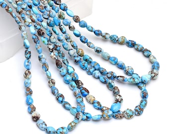 Può includere: Fili di perline ovali nei toni del turchese, marrone e crema. Le perline hanno un motivo maculato e sono infilate insieme, creando una collana o un componente di gioielleria. Le perline sono esposte su sfondo bianco.