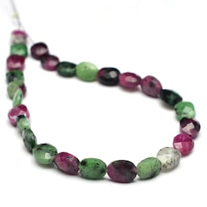 May include: A strand of oval-shaped green and pink gemstone beads. The beads are faceted and have a natural, irregular shape.