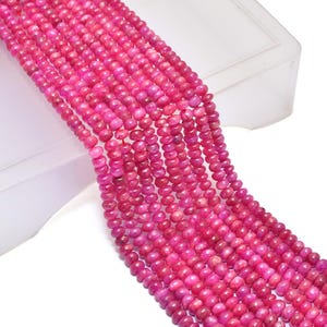 Könnte beinhalten: Eine Strähne aus rosafarbenen Edelsteinperlen. Die Perlen sind rund und haben eine glatte, polierte Oberfläche. Die Perlen sind auf einem durchsichtigen Faden aufgefädelt.