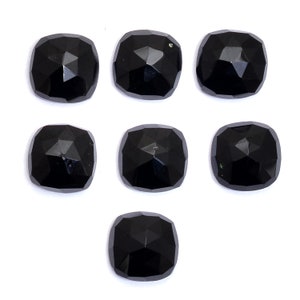 May include: Seven black cushion-cut gemstones with a faceted finish. The gemstones are arranged in a staggered pattern on a white background.