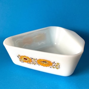May include: White ceramic baking dish with a triangular shape and a floral design featuring yellow and orange flowers with brown stems and leaves.