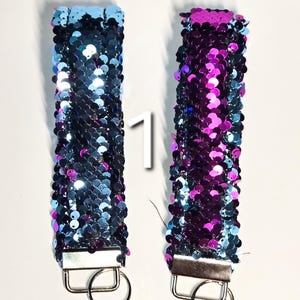 May include: Two reversible sequin keychains, one blue and one purple. The keychains have a silver metal ring.
