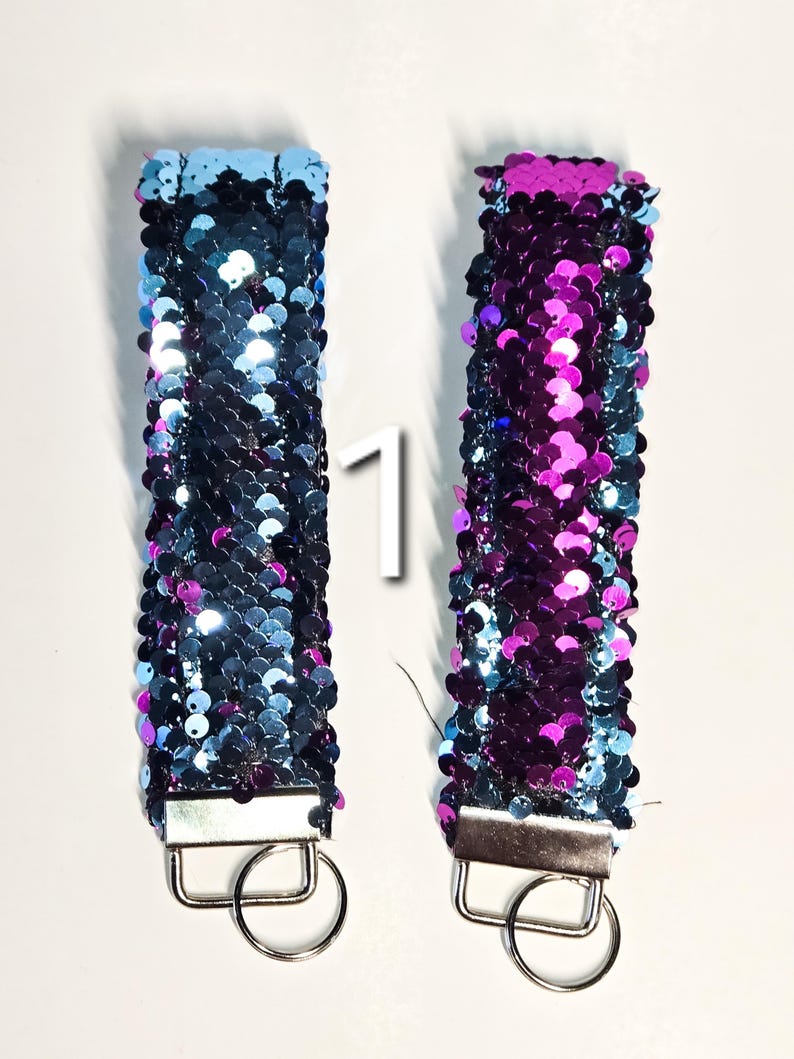 May include: Two reversible sequin keychains, one blue and one purple. The keychains have a silver metal ring.