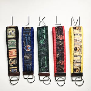 May include: Five colourful keychains with different house crests from the Harry Potter universe. Each keychain features a different house crest and a key ring. The keychains are blue, green, red, and yellow.