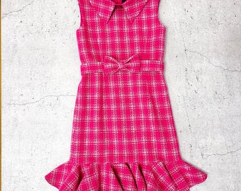 May include: A pink and white plaid sleeveless dress with a ruffled hem and a bow at the waist.