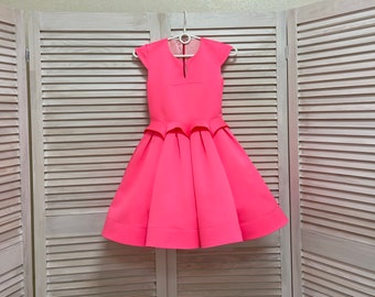 May include: A bright pink dress with a fitted bodice and a full skirt. The dress has short sleeves and a round neckline.
