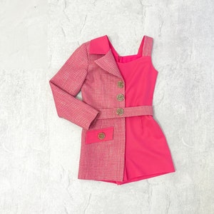 May include: A pink and white tweed blazer with a matching pink skirt. The blazer has a collar, long sleeves, and gold buttons. The skirt has a high waist and a straight silhouette.