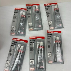 May include: Six tubes of Loctite SI 594 White RTV silicone adhesive sealant, each in a clear plastic package with a red and white header. The tubes are silver with white and red text, and contain 2.7 fl oz.