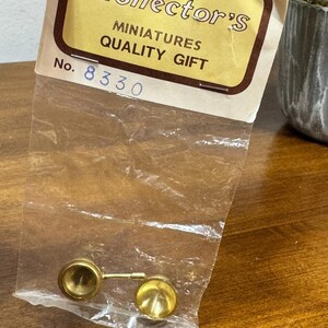 May include: A miniature gold-colored metal spoon and cup set, packaged in a clear plastic bag. The packaging includes the text "Collector's Miniatures Quality Gift" and the number "8330".