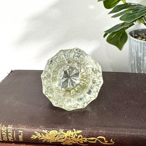 Pomo de puerta antiguo de cristal transparente con acabado de latón desconchado, estilo vintage.