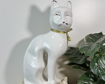 Elegante figura de gato de cerámica blanca con detalles dorados. Estatua felina sentada para decoración.