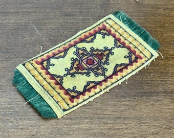 Alfombra miniatura vintage estilo persa para casa de muñecas con flecos amarillos, rojos y verdes.